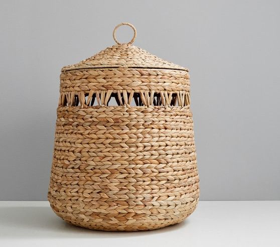 a large woven basket with handles on a white countertop next to a gray wall