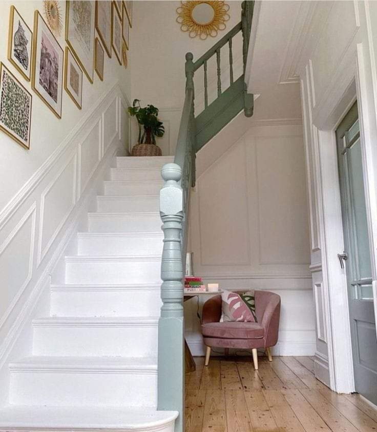 there is a pink chair sitting on the stairs in this house with white walls and wood flooring