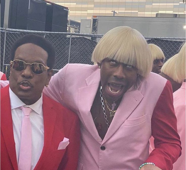 two men in pink suits and sunglasses posing for the camera with one man wearing a red suit