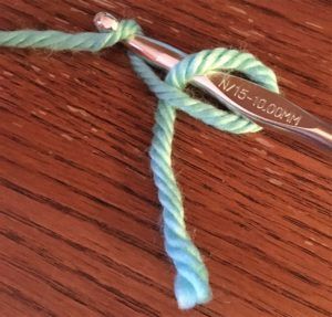 a close up of a pair of scissors on top of a wooden table with yarn