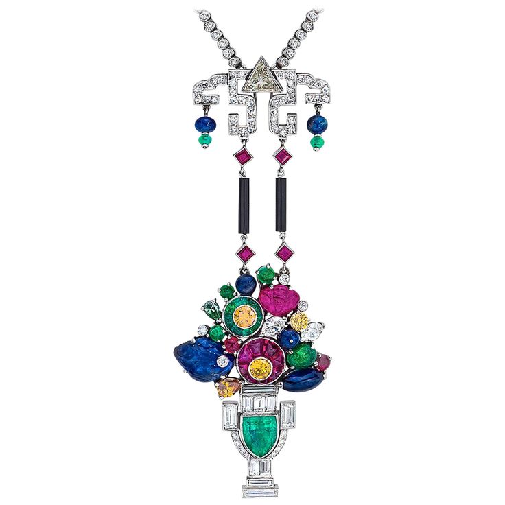 This stunning estate piece is Designed in the art deco Tutti Frutti style. This pendant necklace composed of round brilliant diamonds hand set in Platinum with a Art Deco Tutti Frutti style basket composed of hand carved Rubies, Sapphires and cabochon Emeralds. The fruit filled basket is further enhanced with fancy cut white and yellow Diamonds and a traditional Art Deco motif showcasing a stunning sheild cut Emerald and baguette diamonds. The diamonds go all around the neck, and the necklace cl Egyptian Inspired Jewelry, Necklace Art Deco, Egyptian Inspired, Motif Art Deco, Vintage Pendant Necklace, Genie Bottle, Necklace Art, Necklaces Pendant, Diamond Necklaces