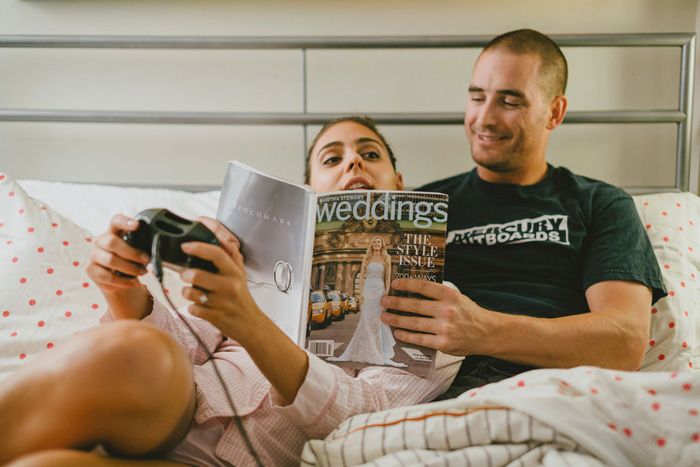 a man and woman laying in bed reading a magazine