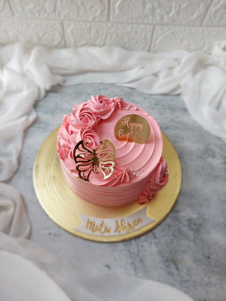 there is a pink cake with gold decorations on the top and bottom, sitting on a silver platter