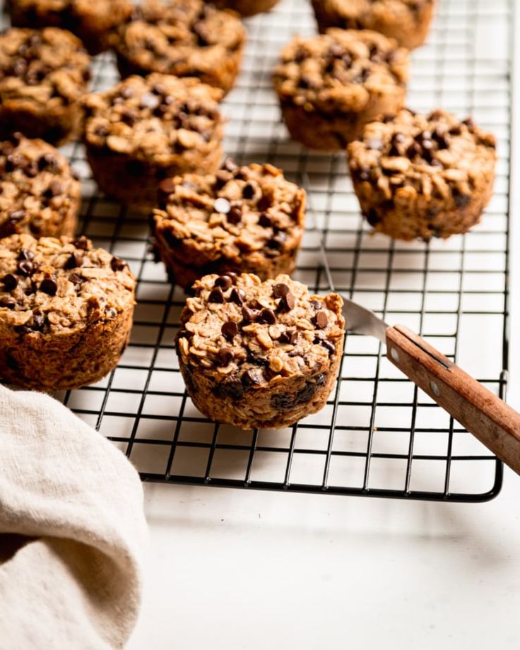 chocolate chip muffins cooling on a wire rack next to cinnamon sticks and a napkin