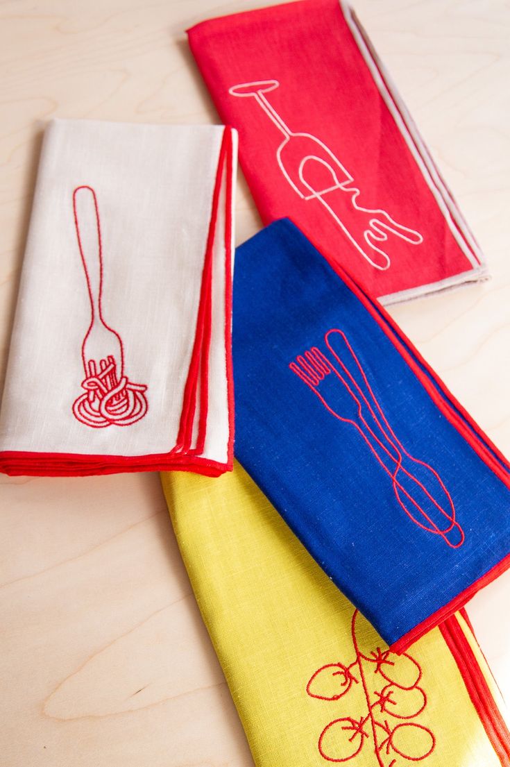 four different colored kitchen towels on a table with utensils and spoons drawn on them