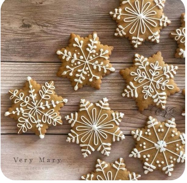 some very pretty decorated cookies on a wooden table with snowflakes in the middle