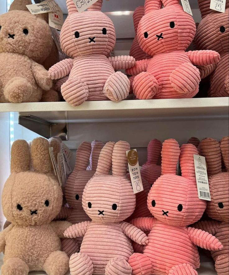 several different colored stuffed animals on display in a store shelf with tags attached to them