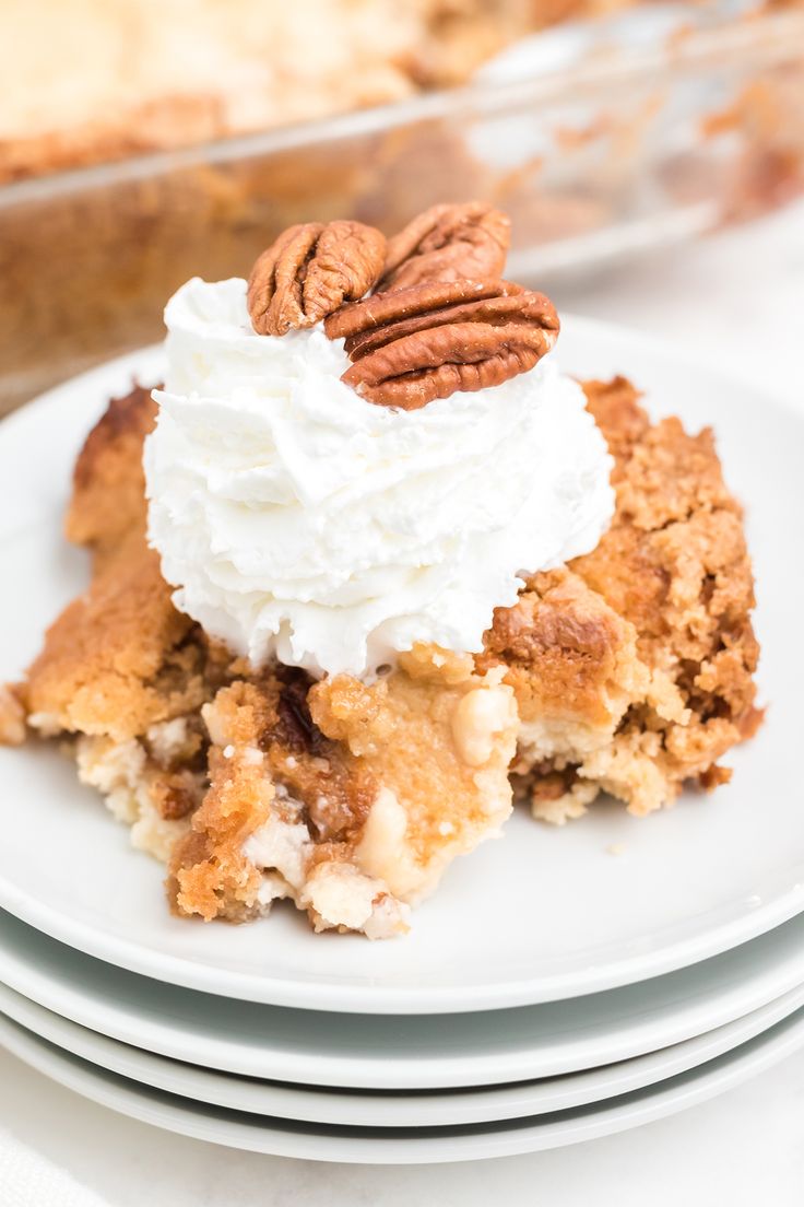 a piece of pie with whipped cream and pecans on top sits on a plate