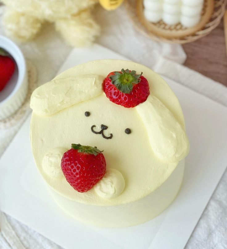 there is a cake with strawberries on it and a teddy bear in the background