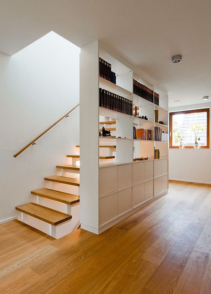 a room with wooden floors and stairs leading up to the second floor, along with bookshelves