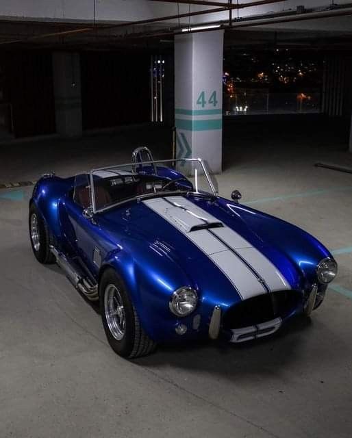 a blue and white sports car parked in a parking garage with no one around it