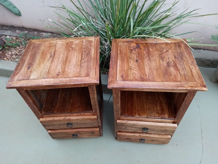 two wooden tables sitting next to each other near a potted plant on the ground