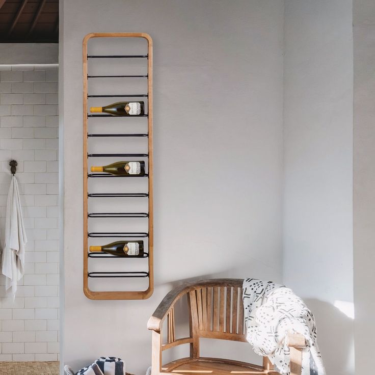 a wooden bench sitting in front of a white tiled wall next to a towel rack