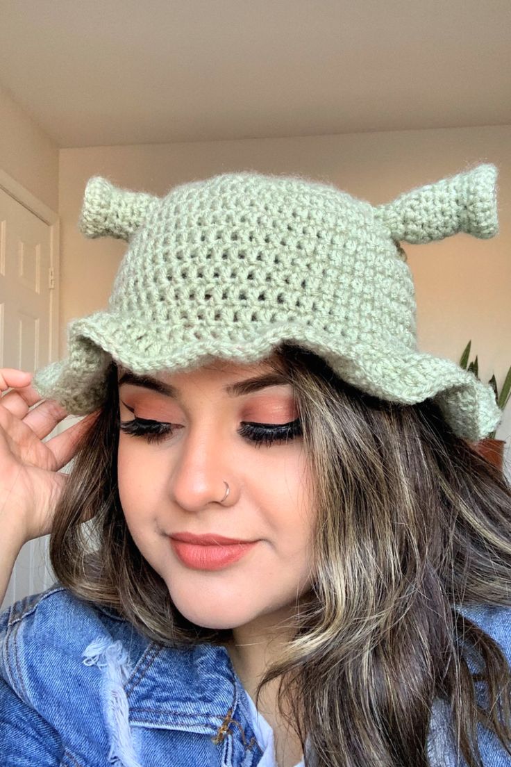 a woman wearing a green crocheted hat with horns on it's head