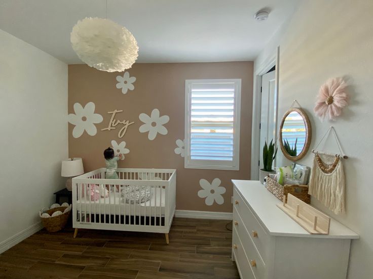 a baby's room with flowers painted on the wall and dressers in front