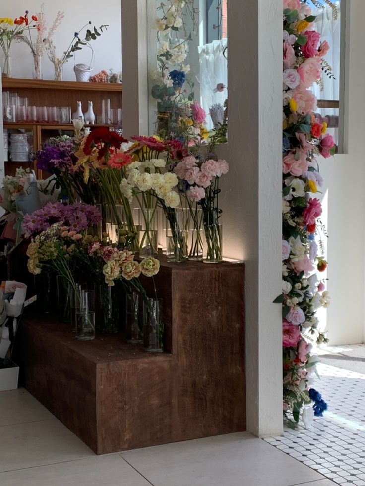 flowers are arranged in vases on the steps to a flower shop's front door