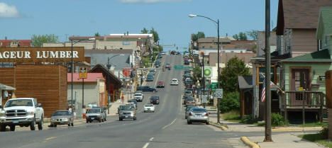 cars are driving down the street in front of shops and businesses on a sunny day