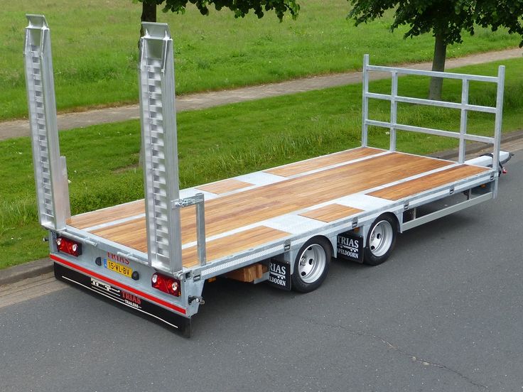 a flatbed trailer is parked on the side of the road in front of some trees