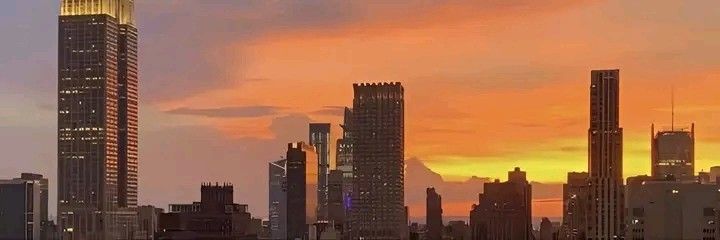 the city skyline is lit up at sunset with skyscrapers in the foreground and clouds in the background