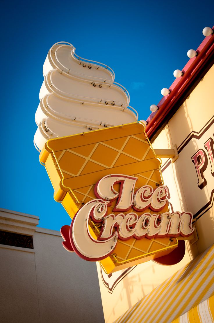 an ice cream shop sign on the side of a building with a blue sky in the background