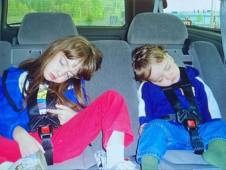 two young children sitting in the back seat of a car