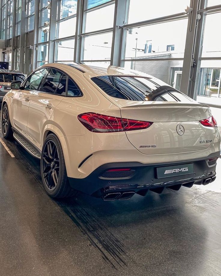 the rear end of a white mercedes suv parked in front of large windows at an airport