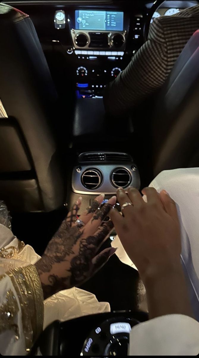 a person sitting in the driver's seat of a car with tattoos on their hands