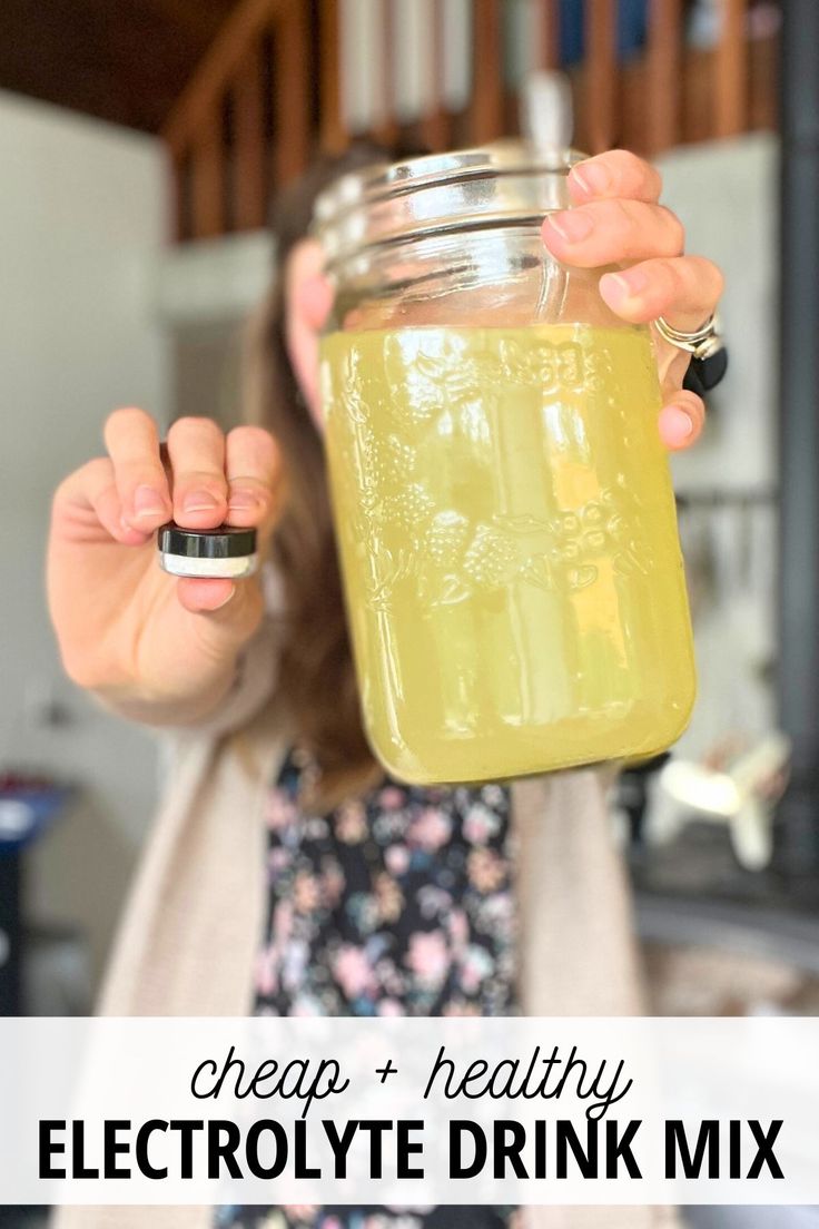 a woman holding up a mason jar filled with electrolyte drink mix