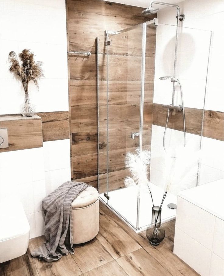 a bathroom with wooden walls and flooring has a white bathtub next to the shower