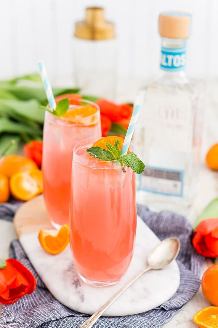 two glasses filled with pink lemonade and mint garnish on a marble platter