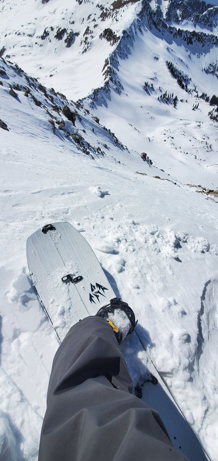 a snowboarder's feet in the snow on top of a snowy mountain