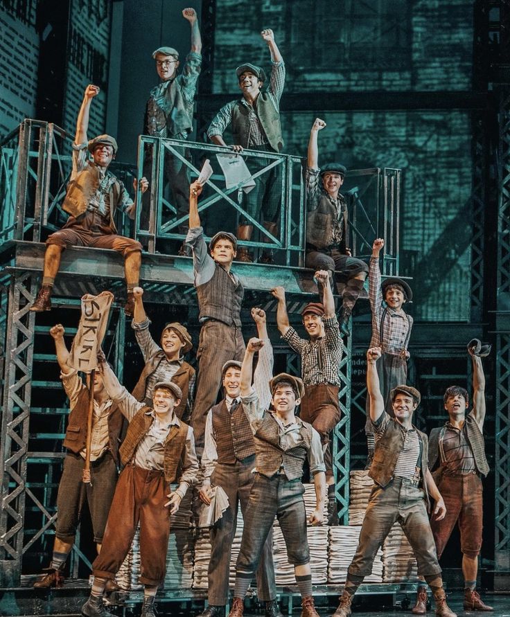 a group of young men standing on top of a stage with their arms in the air