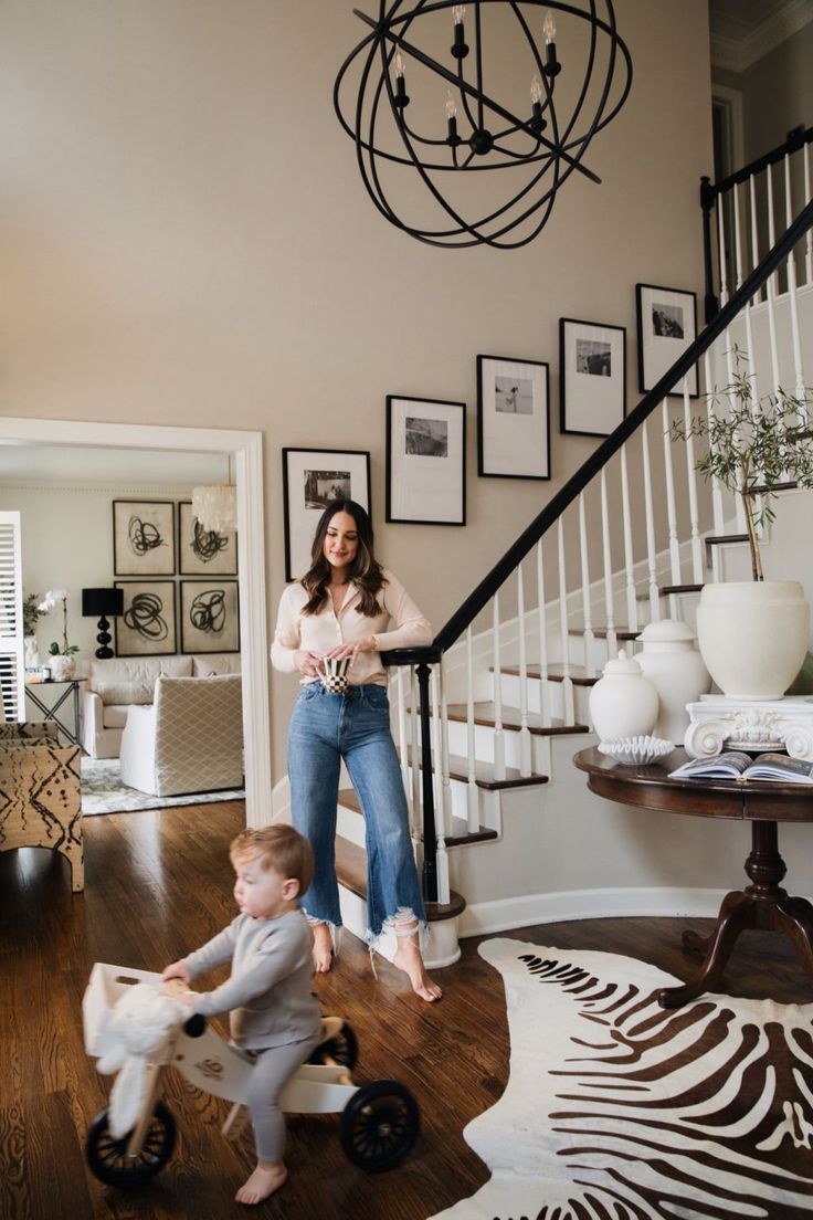 a woman standing on top of a wooden floor next to a baby