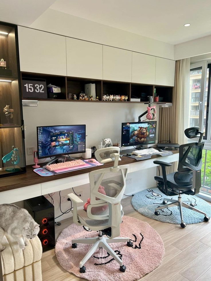 a desk with two computer monitors and a chair in front of it, next to a window