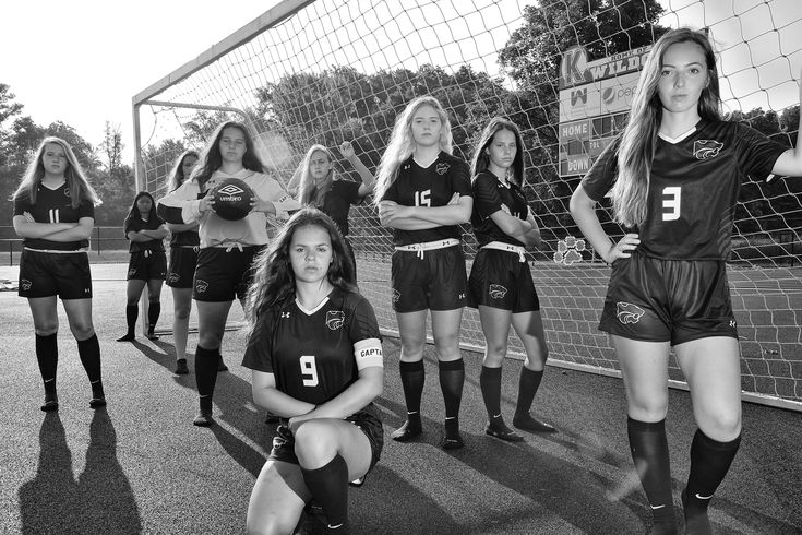 a group of young women standing next to each other in front of a soccer net