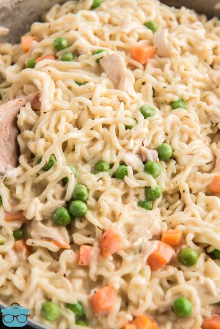 chicken noodle salad with peas and carrots in a skillet