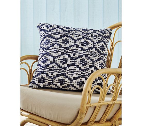 a rattan chair with a blue and white pillow on it's backrest