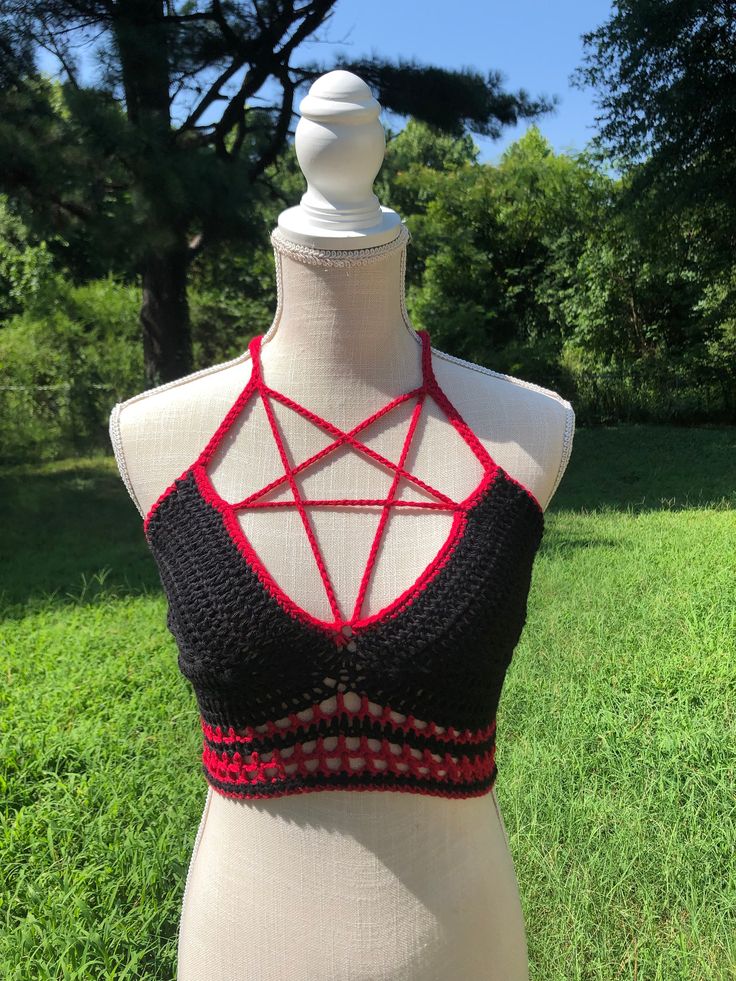 a white mannequin wearing a black and red top with an intricate design on it