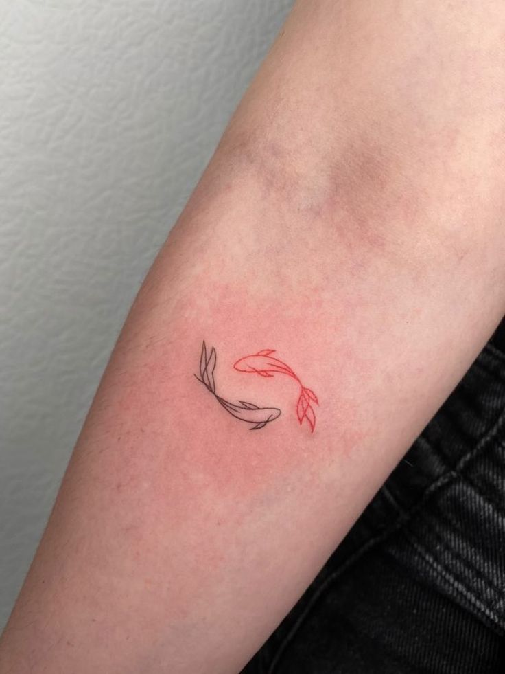 a red and black koi fish tattoo on the left upper half of the arm