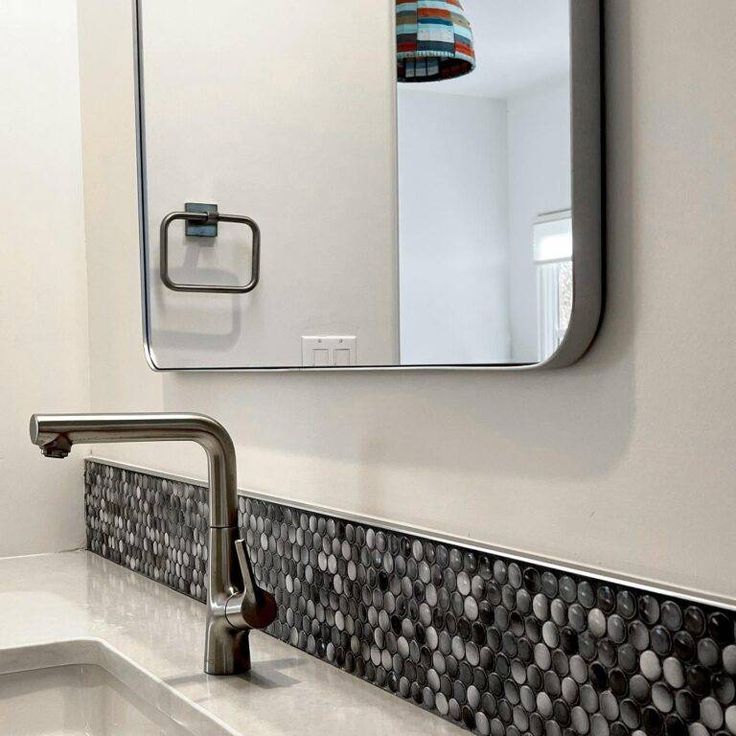 a bathroom sink sitting under a mirror next to a faucet mounted on a wall