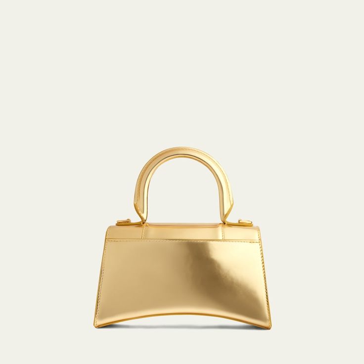 Balenciaga "Hourglass" satchel in mirror calfskin leather. Rolled top handle. Removable, adjustable shoulder strap. Flap top with hanging "B" hardware; snap closure. Exterior, slip compartment at back. Interior, one slip pocket. Approx. 5.1"H x 7.5"W x 3.2"D. Spot clean. Made in Italy. High-end Gold Top Handle Shoulder Bag, Gold Flap Bag With Branded Hardware For Formal Occasions, High-end Gold Satchel With Gold-tone Hardware, High-end Gold Crossbody Flap Bag, High-end Gold Shoulder Bag With Detachable Strap, Evening Satchel With Gold-tone Hardware And Round Handle, Designer Gold Flap Bag With Detachable Handle, Designer Flap Bag With Handles For Evening, Modern Handheld Bags With Branded Hardware