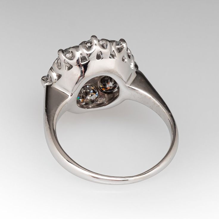 This vintage diamond ring is centered with one (1) old European cut diamond set into a four-prong setting. The center stone is bordered with eight (8), bead set, old European cut diamonds. The ring measures 13.8mm at the top, rises 7.6mm above the finger, tapering to 1.3mm wide and 0.9mm thick at the base of the shank. It is currently a size 4.25. Two of the side diamonds have very small chips that cannot be seen without magnification. Vintage Diamond Ring, Vintage Diamond Rings, Bead Set, European Cut Diamonds, Diamond Cluster Ring, Diamond Set, Diamond Cluster, Vintage Diamond, Cluster Ring