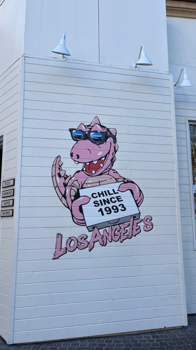 a large mural on the side of a building depicting a cartoon character wearing sunglasses and holding a sign that says los angeles