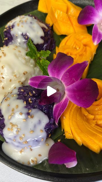 a black plate topped with three different types of desserts covered in icing and flowers