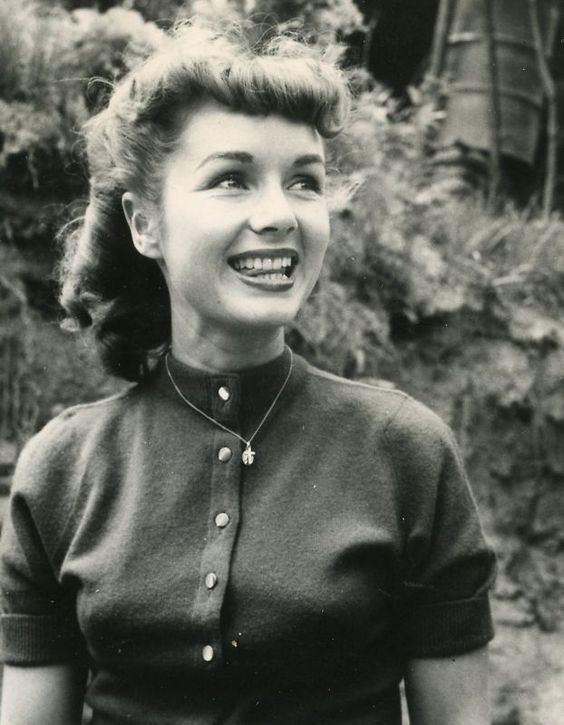 an old black and white photo of a woman smiling