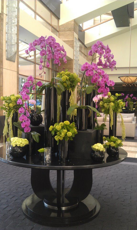 there are many flowers that are in the vases on this glass table and one is purple