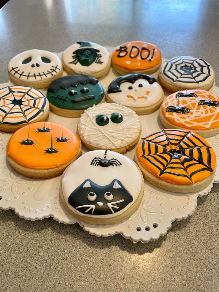 decorated cookies are arranged on a white platter with spider webs and jack - o'- lantern faces