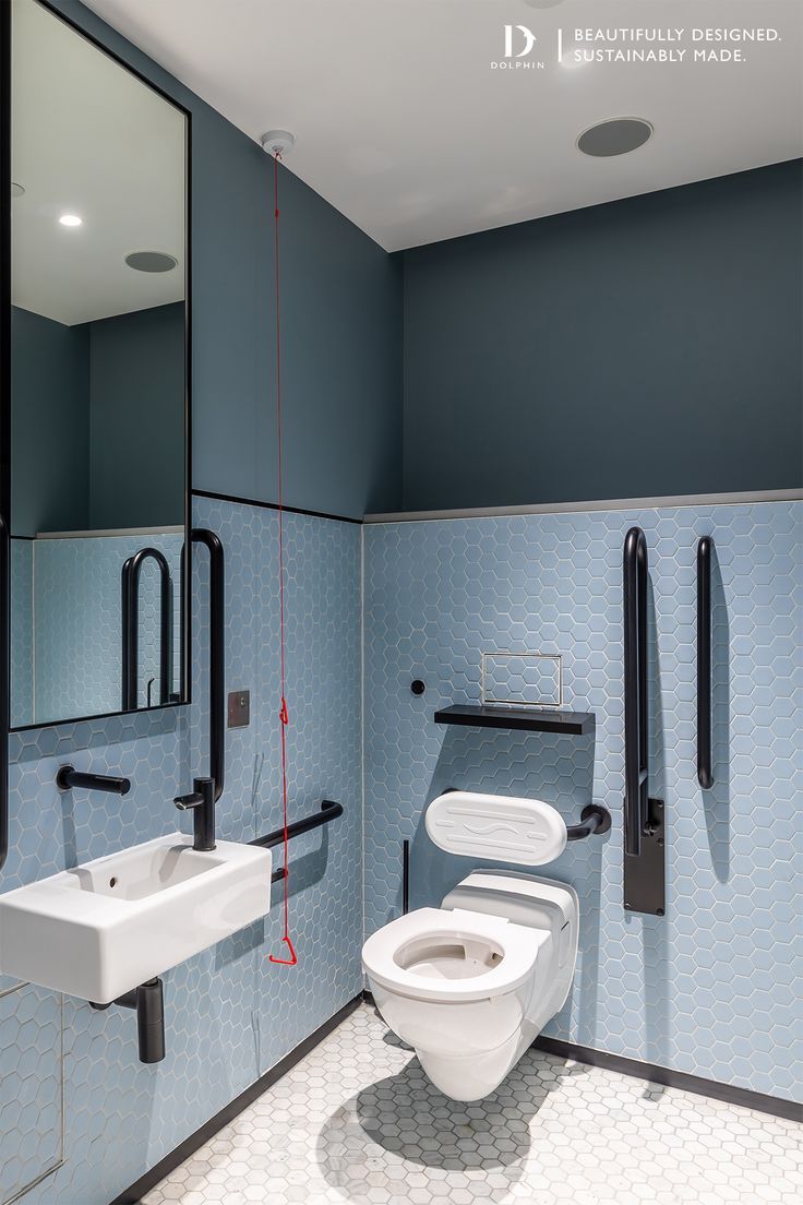 a bathroom with blue and white tile walls, black handles on the door, and a mirror above the toilet