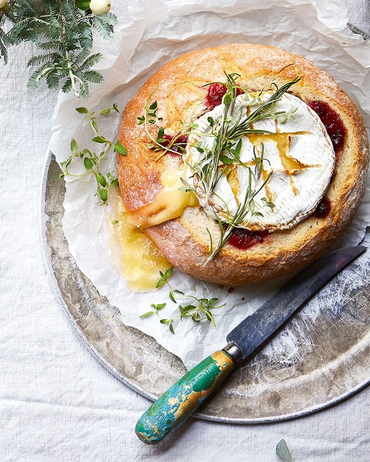 a pastry with cheese and fruit on top sits on a plate next to a knife