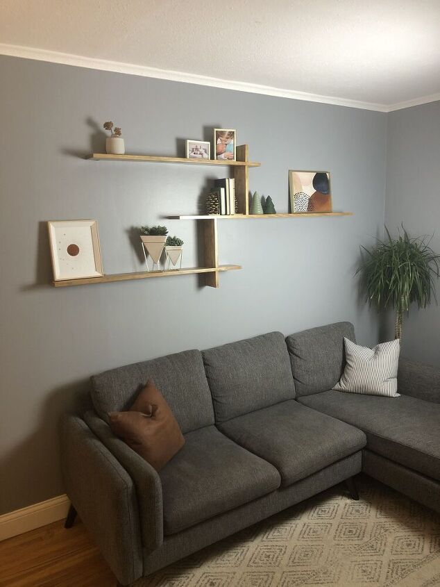 a living room with a gray couch and some shelves on the wall above it,